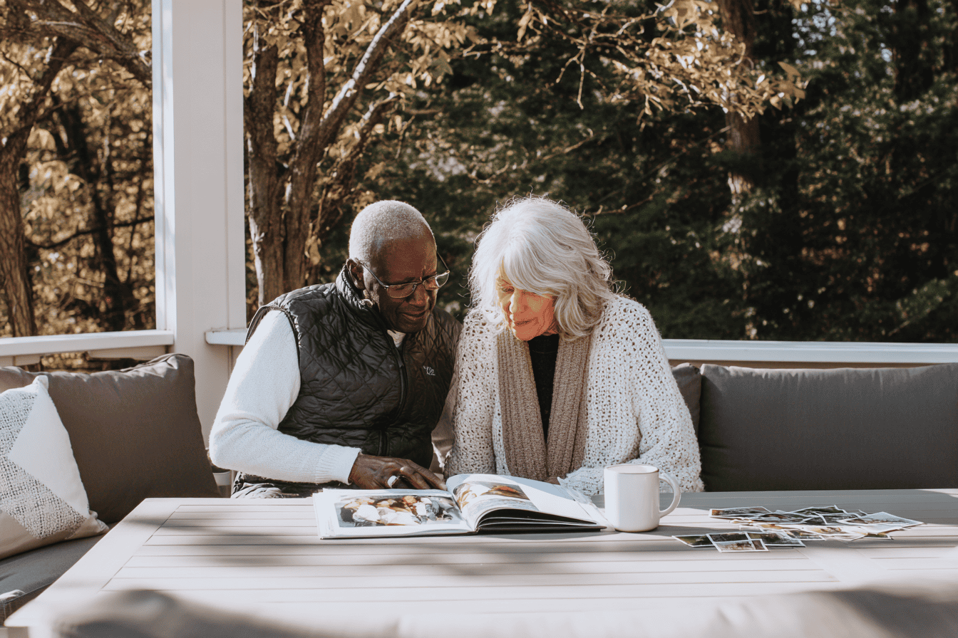 Older couple reading life story together on patio